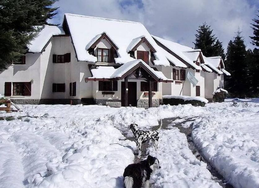 Posada del Angel in San Carlos de Bariloche, snow-covered chalet-style hotel exterior with pine trees