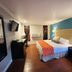 Casa Blanca Hotel - Orange room with king bed, wall-mounted TV, full-length mirror and blue accent wall