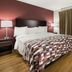 Red Roof Inn & Suites Knoxville East room with queen bed, wood floors and burgundy accent wall in Knoxville