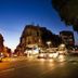 Sun City Hotel in Tel Aviv at dusk, with city street traffic and illuminated buildings