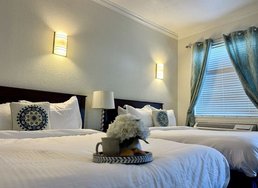 Athens Hotel Suites in Houston guest room with two beds, wall sconces, and a window with curtains