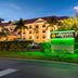 La Quinta Inn & Suites by Wyndham Bonita Springs Naples N. exterior at dusk with palm trees and lit sign