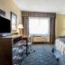 Regency Inn & Suites New London Mystic guest room with bed, desk, TV, and window seating in New London