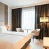 AC Hotels by Marriott Inverness guest room with twin beds, window seating, and floor lamp