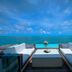 Diamonds Thudufushi Beach & Water Villas oceanfront deck with sofas overlooking the turquoise sea