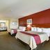 Red Roof Inn Vincennes room with two beds, desk, chair, and a red accent wall