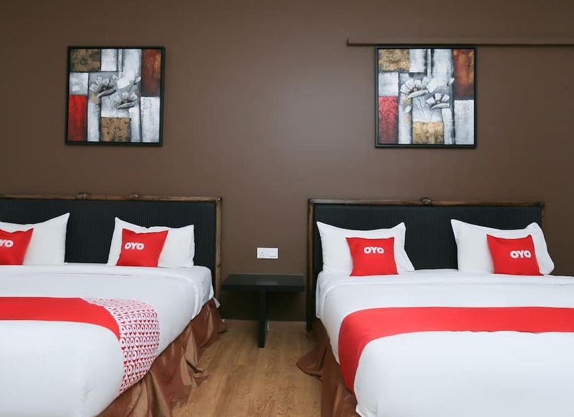 OYO 89915 East Mount Hotel in Kukup: twin beds in a simple hotel room with framed wall art