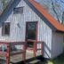 Grindsted Aktiv Camping cabin with red-railed deck and white outdoor chairs in Grindsted