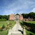 The Coed-Y-Mwstwr Hotel in Bridgend with a grand manor house, stone path, and landscaped gardens