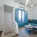 Aegean Blue Suites in Pyrgos Kallistis with teal sofa, coffee tables, and blue balcony doors in a bright suite