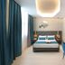 The Hive Hotel Rome room with king bed, teal curtains, desk, blue chair and modern ceiling light