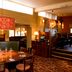 Premier Inn Northampton West - Harpole restaurant interior with round table, booth seating and warm lighting
