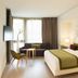 The Passage - Urban & Lifestyle Hotel Basel guest room with king bed, sofa, chair, and window view
