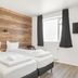 Stay Apartments Einholt Reykjavik guest room with twin beds, wood accent wall and wall-mounted TV