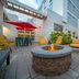 Home2 Suites by Hilton Saratoga Malta patio with fire pit, seating, and red umbrella in Malta
