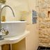 Villa Olivia Split bathroom with wall-mounted sink, shower, and rustic stone wall