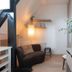 Hotel Het Oude Raadhuis in Castricum: cozy loft-style room with dark sofa, lamp, shelves, and oval mirror