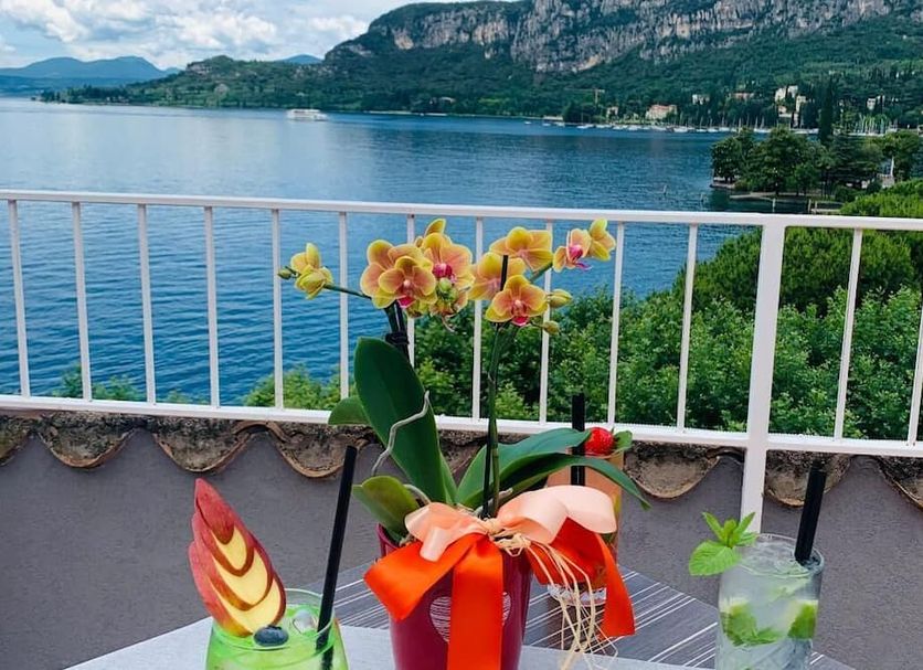 Hotel Conca D'Oro S in Garda terrace with lake and mountain views, balcony flowers and table decor