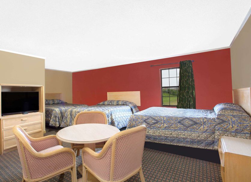 Knights Inn Wildersville room with three beds, round table, TV, and window view