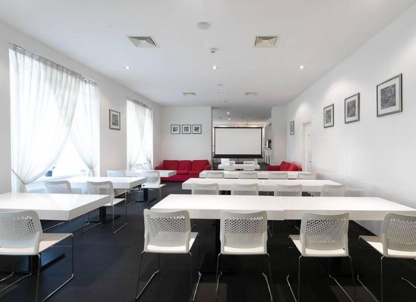 My Hotel Apollon Prague meeting room with long white tables, red seating, and projector screen