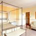 Villa Ambrosina in Impruneta: four-poster bed in a warm guest room with sofa and bedside lamps