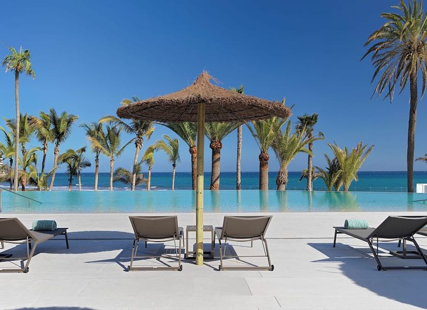 Paradisus Gran Canaria pool deck with loungers, palapa umbrella and ocean view in Maspalomas