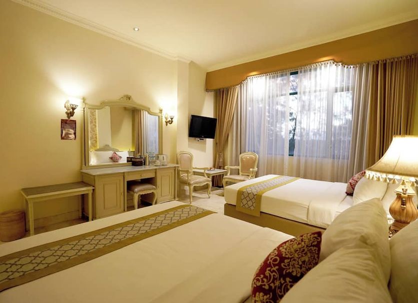 Hotel Indah Palace Solo guest room in Surakarta City with twin beds, vanity, and large window