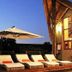 Pilanesberg Private Lodge in Pilanesberg with poolside loungers and umbrella beside a lit lodge exterior