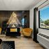 Hotel Zazz Albuquerque lounge with gold chairs, black sofa, geometric mural, and city view window
