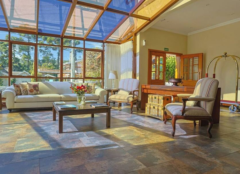 Hotel Le Renard in Campos do Jordão: sunlit lounge with glass ceiling, sofa, armchairs and coffee table