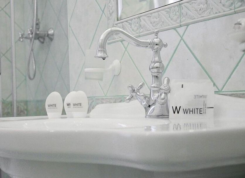 Sleep In Rome Ludovisi bathroom sink with chrome faucet, shower, and branded toiletries in Rome