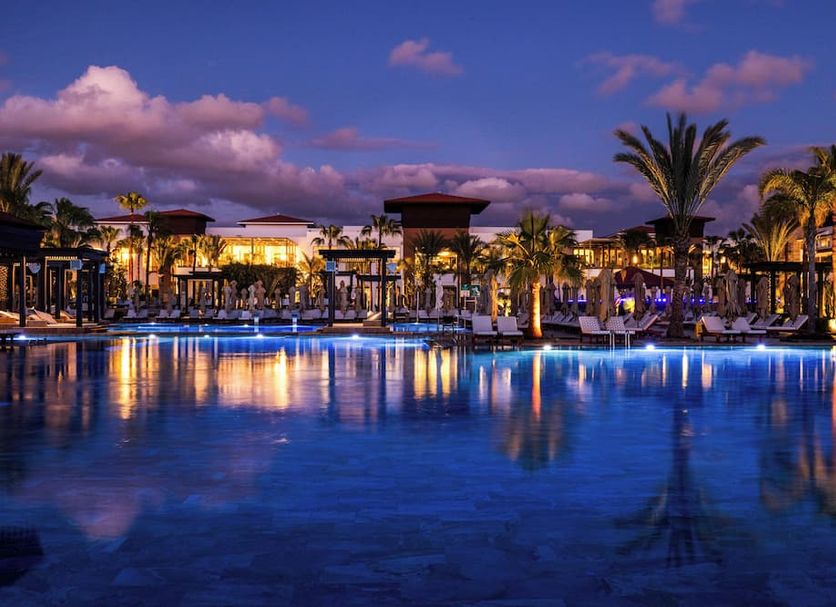 Riu Palace Tikida Agadir in Agadir: illuminated outdoor pool with palm trees at dusk