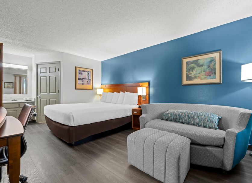 Baymont by Wyndham Tuscaloosa guest room with king bed, sofa, and blue accent wall