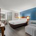 Baymont by Wyndham Tuscaloosa guest room with king bed, sofa, and blue accent wall