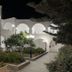 Hotel Lodos in Karterados with white arched courtyards, garden paths and lit exterior at night