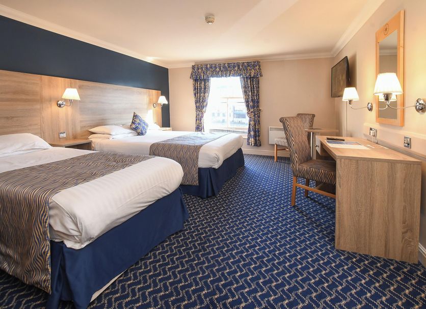 The Queens Hotel York guest room with two twin beds, desk, chairs, and window view