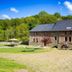 Ferme de Leuze in Somme-Leuze with brick lodge, patio tables, and hammocks on a grassy courtyard