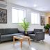 Hotel De Ecobiz Ahmedabad lounge with striped sofa, armchair, coffee table, potted plants and wall art