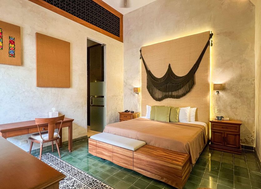 Ya'ax Hotel Boutique in Mérida with a bed, green tile floor, and a decorative wall hanging