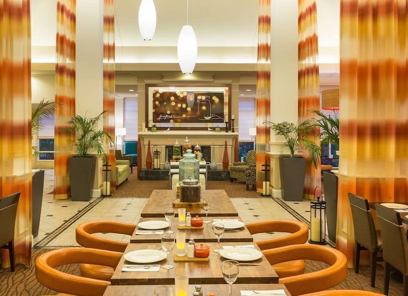 Hilton Garden Inn Daytona Beach-Airport dining area with set tables and orange chairs in Daytona Beach