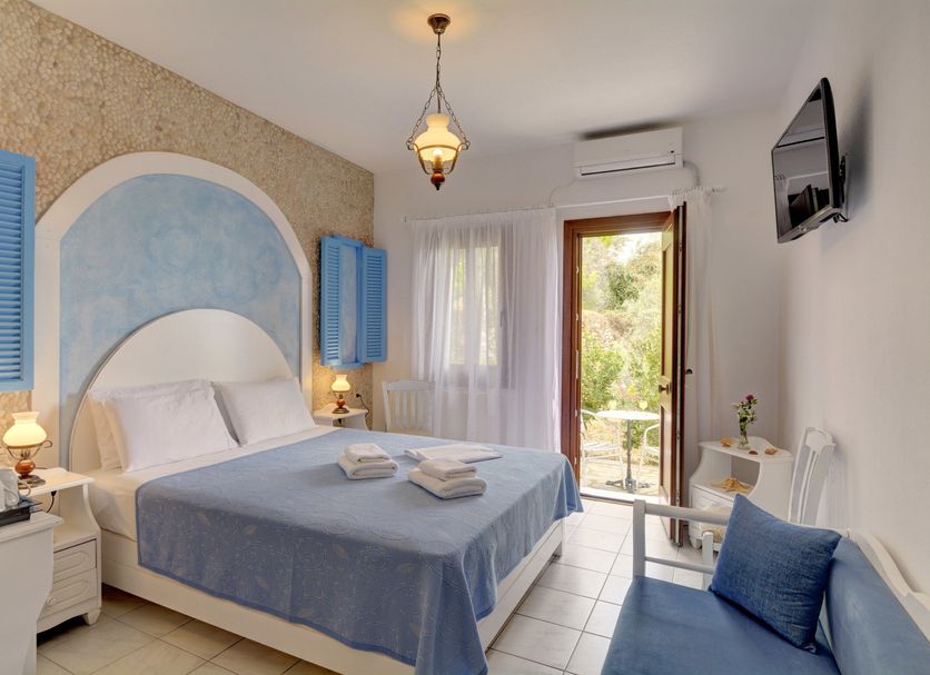Hotel Agnadi room in Chorefto with double bed, blue accents, balcony door and sofa