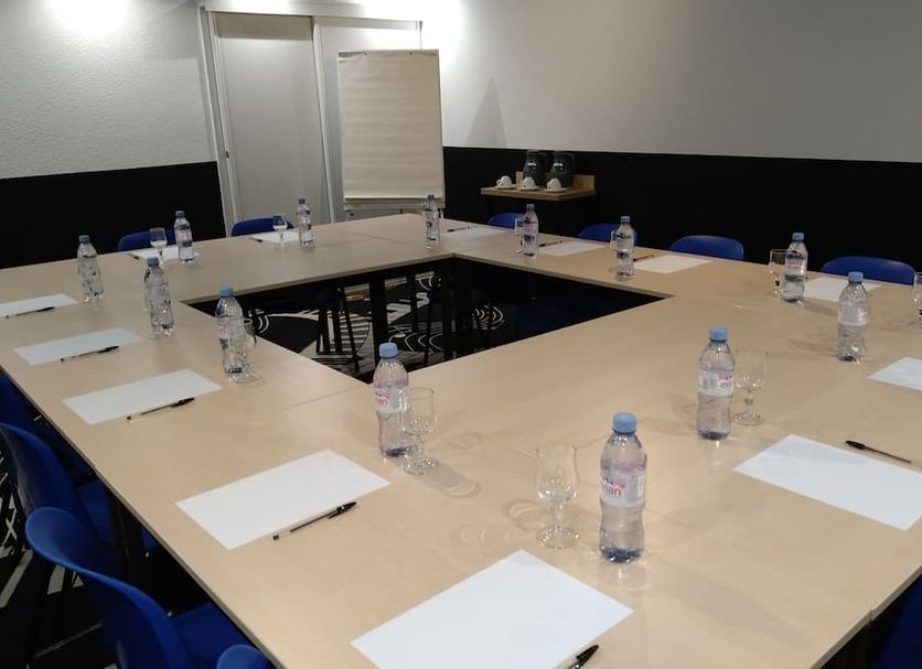 Balladins Beauvais meeting room with U-shaped conference table, chairs, water bottles and notepads
