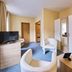 Arador City Hotel in Bad Oeynhausen guest room with armchairs, TV, wardrobe and carpeted floor