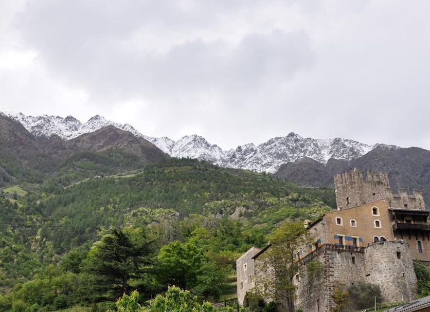 Hotel Weingarten in Naturno with mountain backdrop and hillside castle-like building
