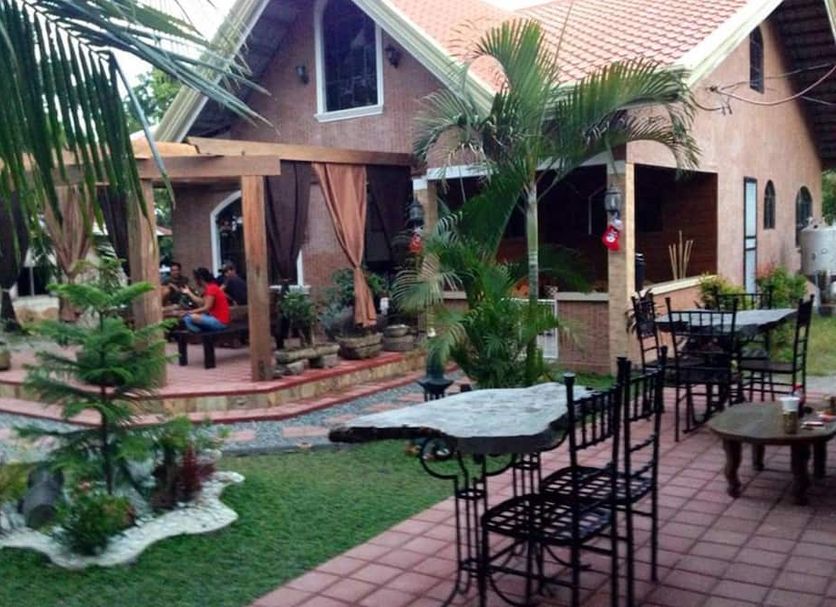 Bognot Lodge Mt Pinatubo Guesthouse in San Jose with tropical courtyard, patio seating, and palm trees