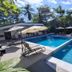 Pool at Hotel Cocomar Beachfront Hotel in Parrita with loungers, umbrellas and tropical trees