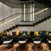 The Murray, Hong Kong lounge with black sofas, colorful pillows, and a staircase under a dotted ceiling.
