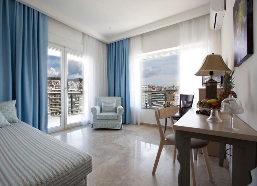 Panorama Junior Suites in Kavála room with city-view windows, chaise lounge, desk and chair