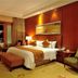 New Century Grand Hotel Kaifeng guest room with king bed, warm wood paneling, and city view at night