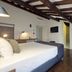 Youroom Corsini Rome guest room with exposed beam ceiling, double bed, and small seating area